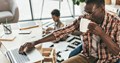 self-employed black father working from home with his son alongside